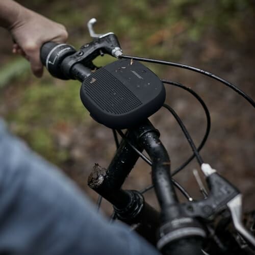 Person holding bike handlebar with attached speaker