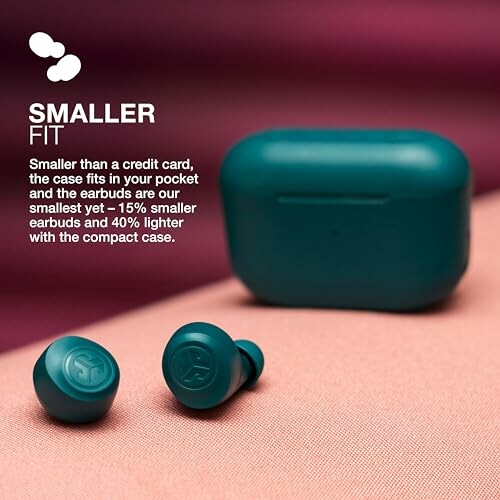 Small teal wireless earbuds with compact case on a pink surface.