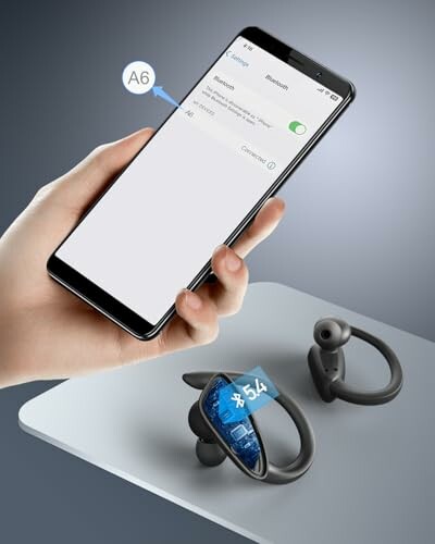 Hand holding a smartphone connecting to wireless earbuds.