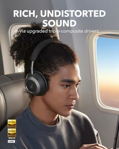 Person wearing headphones on an airplane, text reads 'Rich, undistorted sound via upgraded triple-composite drivers.'