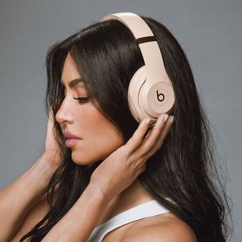 Woman wearing beige over-ear headphones.